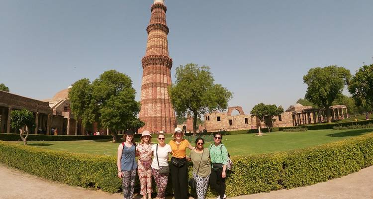 Turistas posando frente a una gran torre histórica de piedra.