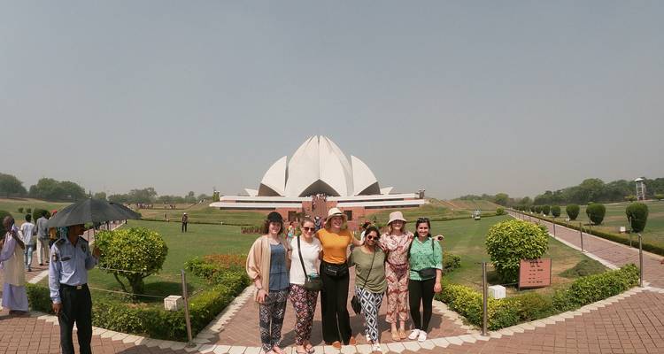 Grupo de turistas posando con el Templo del Loto de fondo.