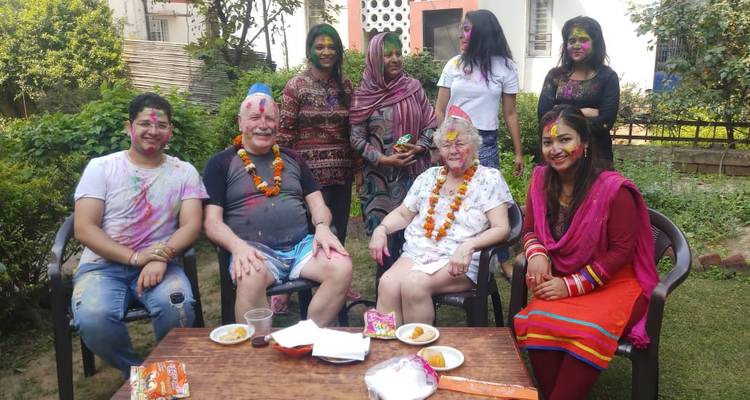 Kleine Gruppe in bunten Holi-Pulvern gekleidet, die im Freien in einer Gartenanlage feiert.