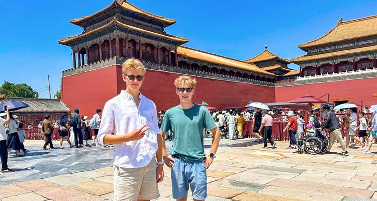 Twee jonge reizigers die nonchalant poseren in de binnenplaats van de Verboden Stad op een zonnige dag.