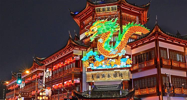 Levendige neondraken-uithangbord verlicht traditionele houten gevelkanten in Shanghais oude stad 's nachts.