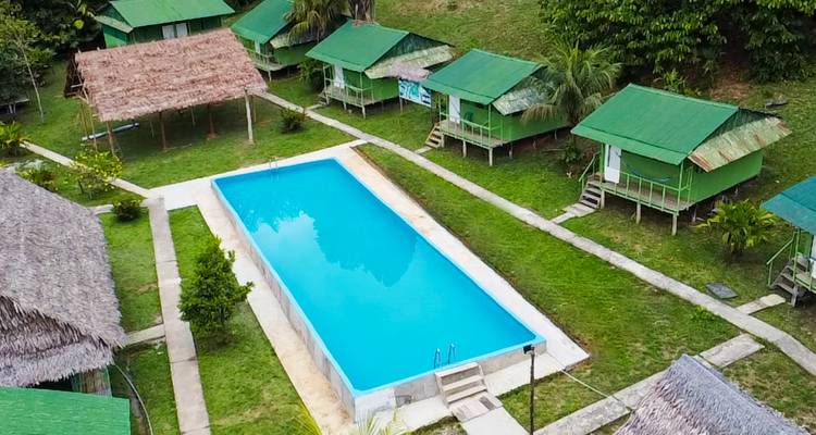 Aerial view of a pool surrounded by cabins and greenery.