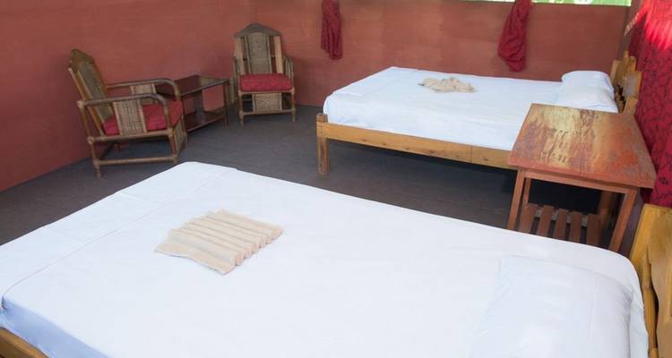Two beds in a room with chairs and a table.