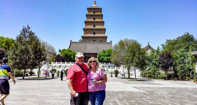 Un couple posant devant une pagode dans un jardin paysager.