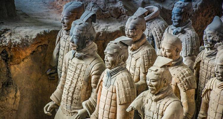 Vista de cerca de los Guerreros de Terracota parados en una fosa de excavación, mostrando detallados soldados de arcilla antigua.