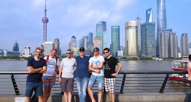 Grupo de hombres posando frente al horizonte de una ciudad al otro lado de un río.