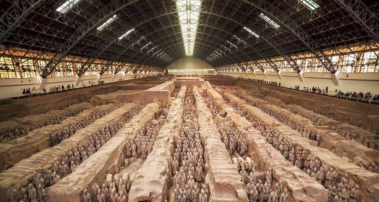 Un enorme hangar interior que alberga miles de Guerreros de Terracota alineados en filas ordenadas bajo un techo abovedado.