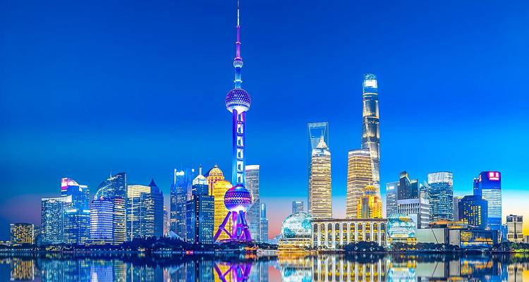 Vibrante horizonte nocturno de Shanghai con la Torre Perla Oriental y los rascacielos modernos reflejándose en el río Huangpu.