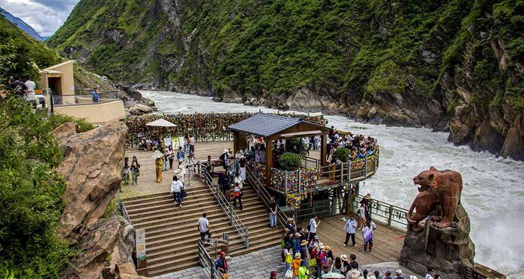 Visitors gather on a wooden viewing deck beside the roaring Jinsha River deep within Tiger Leaping Gorge.
