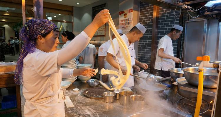 Chefs préparant des nouilles chinoises traditionnelles dans une cuisine.