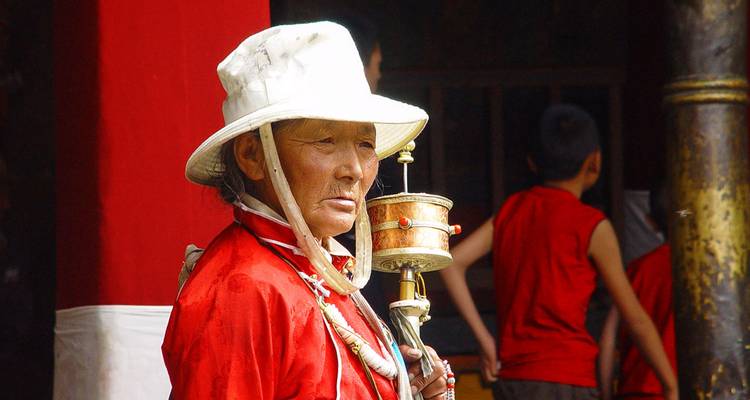 Personne tenant un moulin à prières en tenue traditionnelle.