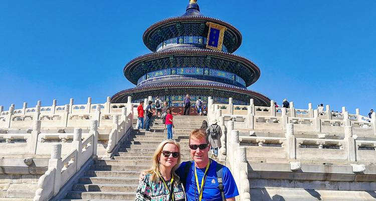 Des touristes posent sur les marches d'un temple aux carreaux colorés.