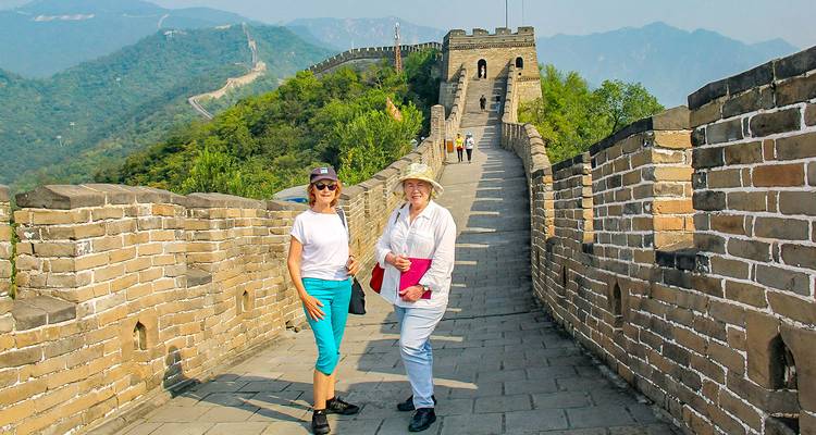 Deux dames posant sur la Grande Muraille avec un paysage montagneux.
