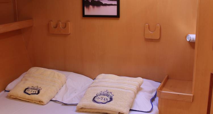 Cozy cabin interior on a yacht with bed and decorated towels.