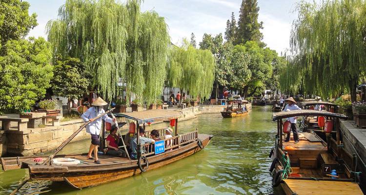 Bateaux traditionnels en bois sur un canal pittoresque bordé de saules.