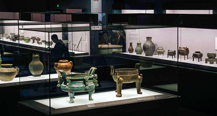 Salle d'exposition présentant des vases en bronze de la Chine ancienne à l'intérieur d'un musée faiblement éclairé.