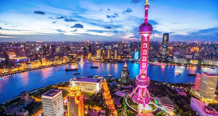 Panorama vibrante del atardecer del horizonte de Shanghai con la icónica Torre Perla Oriental iluminada dominando el río Huangpu.