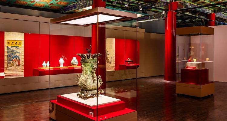 Galerie de musée bien éclairée exposant des artefacts de la Chine ancienne dans des vitrines modernes en verre.