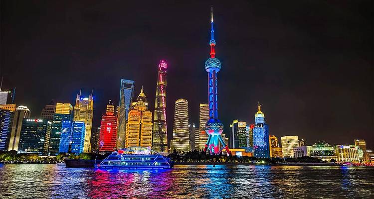 Nachtelijke panorama van Shanghais neonverlichte skyline met levendige kleuren die weerspiegelen in de Huangpu River.