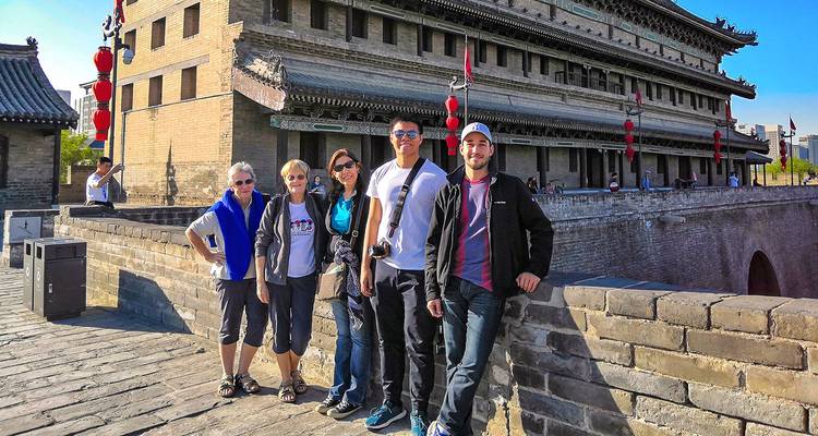 Grupo de turistas posando junto a una muralla antigua.