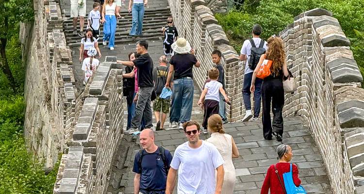 Besucher, die entlang eines restaurierten Abschnitts der Chinesischen Mauer zwischen Steinbefestigungen spazieren