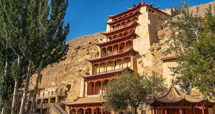 Mehrstöckige Tempelfassade der Mogao-Höhlen, in die Sandsteinklippe eingebaut, unter blauem Himmel