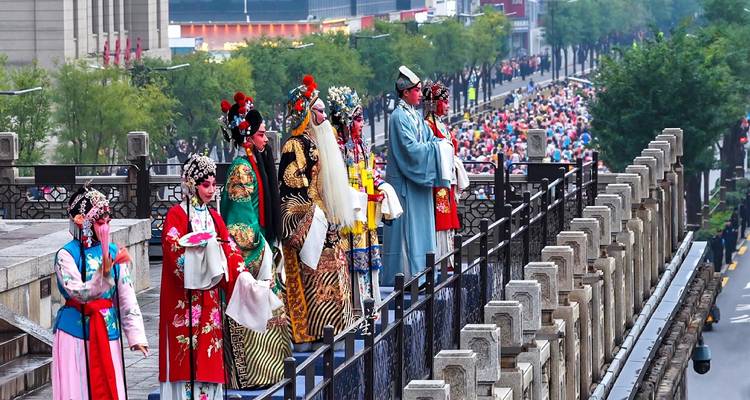 Los intérpretes de ópera tradicional con túnicas ornamentadas se paran en lo alto de la muralla de la ciudad de Xi'an para el desfile del festival.
