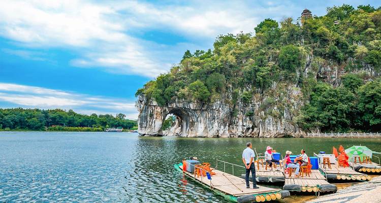 Los turistas en una plataforma flotante admiran el arco de la Colina de la Trompa del Elefante al otro lado de un río tranquilo