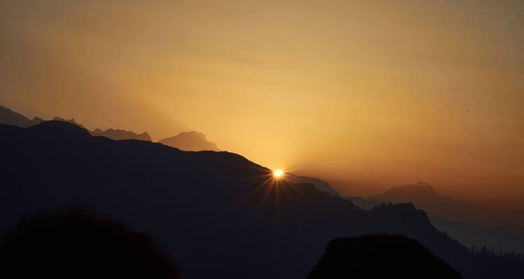 Soleil levant sur des chaînes de montagnes brumeuses.