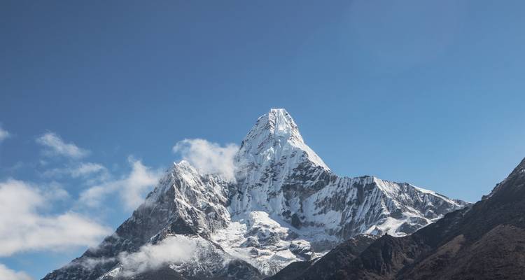 Gros plan d'un sommet de montagne avec de la neige sous un ciel bleu.