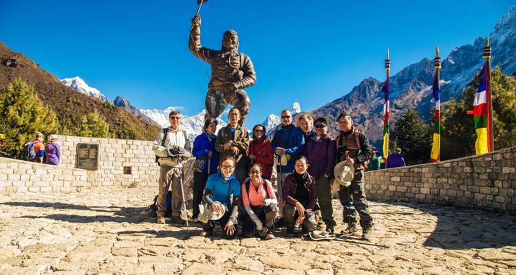Groupe posant devant une statue dans une région montagneuse.