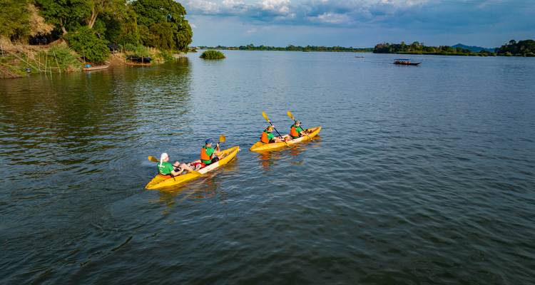 Group kayaking on a calm lake with verdant surroundings.