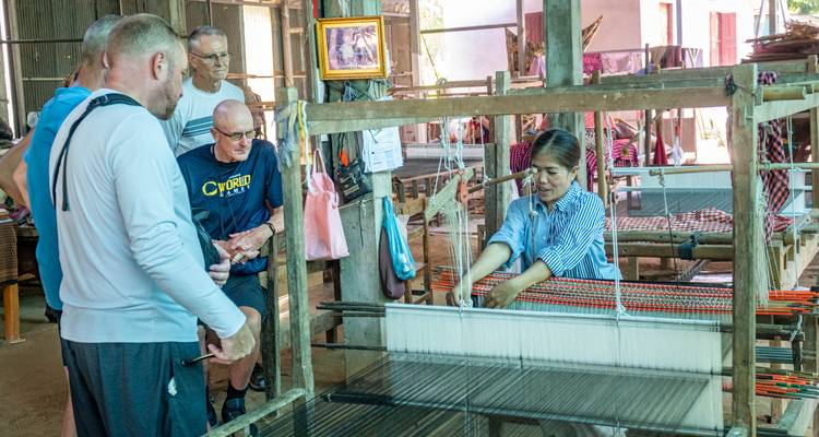 A woman demonstrating traditional weaving in front of a group of visitors.