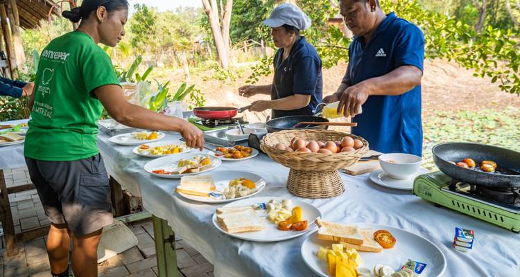 Des personnes préparant de la nourriture à une table remplie de divers plats et ingrédients.