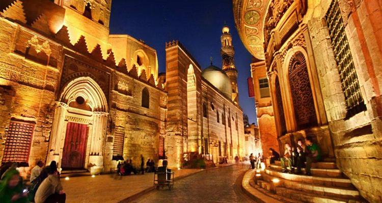 Rue Al-Muizz illuminée la nuit avec des gens.