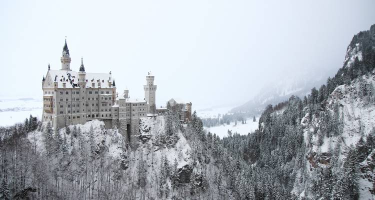 Le château de Neuschwanstein perché sur une colline enneigée.