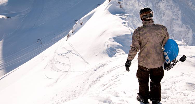 Snowboardeur debout au sommet d'une montagne enneigée.