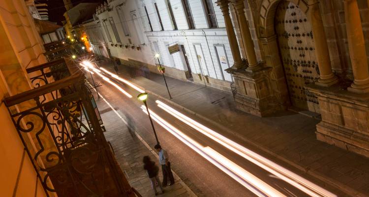 Photographie de longue exposition nocturne d'une rue coloniale à Sucre avec les traînées lumineuses des voitures
