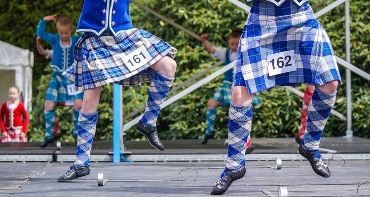 Des danseurs écossais en tenue traditionnelle se produisent sur scène.