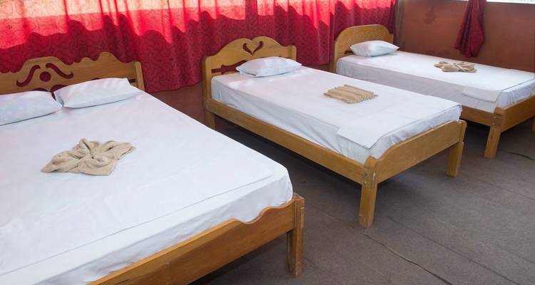 Three single beds with simple white linens in a room.