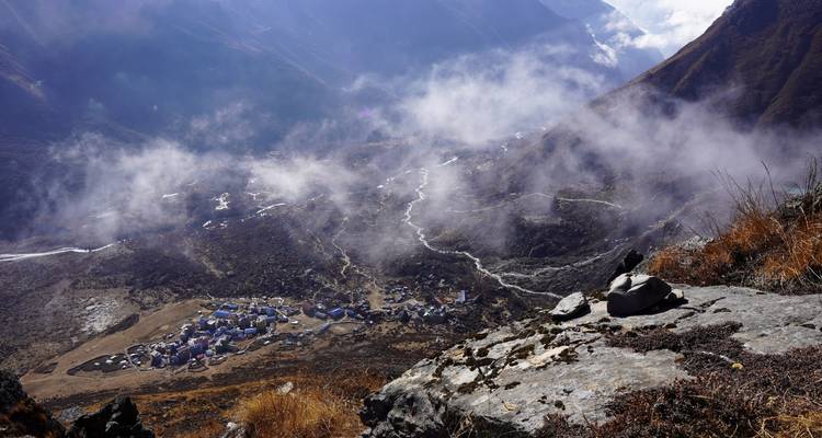 Luftaufnahme eines Bergdorfes, umgeben von nebeligen Hügeln.