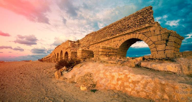 Antiguo acueducto de piedra contra una puesta de sol vibrante.
