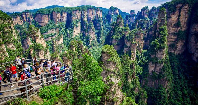 Toeristen op een houten uitkijkplatform met uitzicht op dramatische kwartszandsteen zuilen in het Zhangjiajie bospark