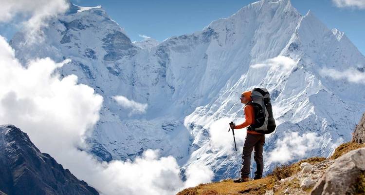 Hiker overlooking snowy, rugged mountains.