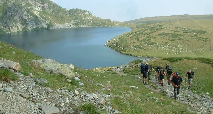Des randonneurs qui gravissent une colline près d'un lac.