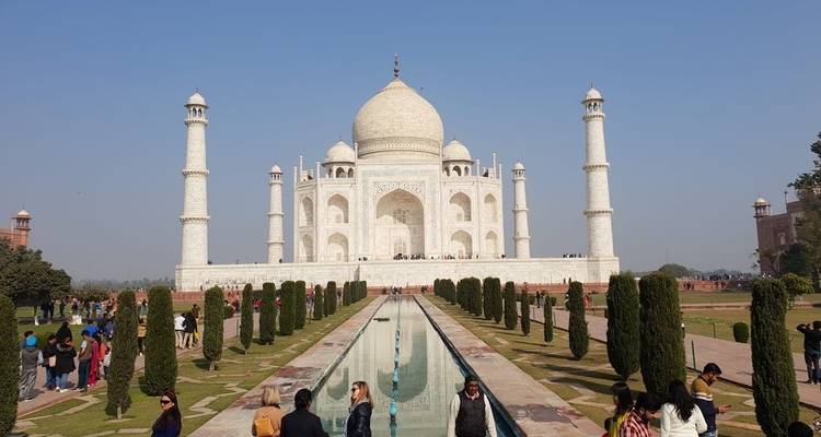 Tourists visiting the Taj Mahal with reflection in water.