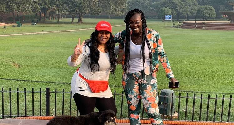 Two women posing in a park with a dog.