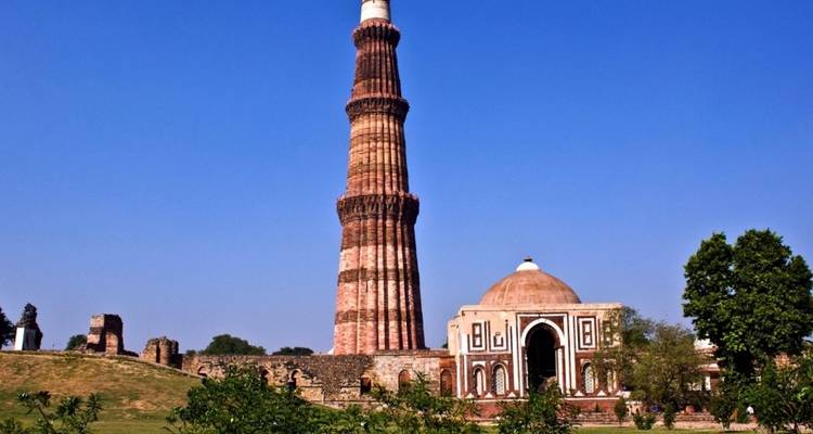 Qutub Minar and an adjacent structure with a clear blue sky.
