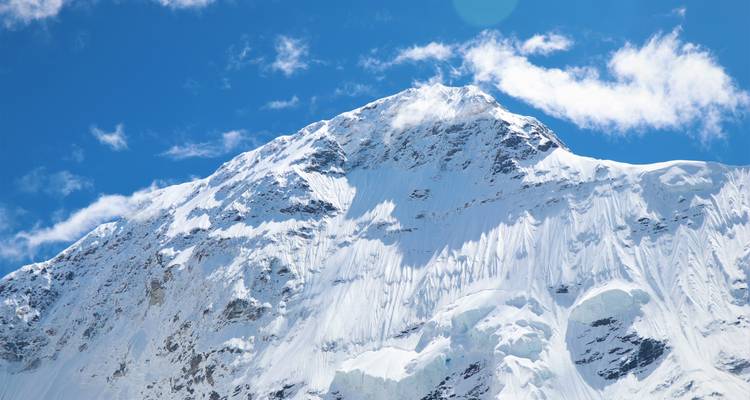 Un pico de montaña cubierto de nieve contra un cielo azul.