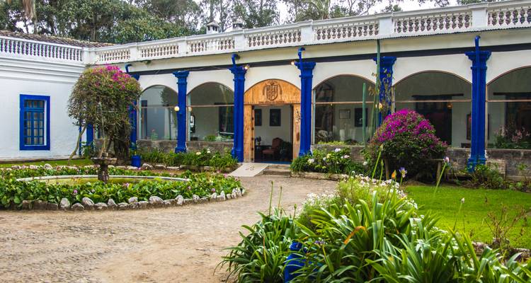 Patio con flores vibrantes y un encantador edificio azul y blanco.